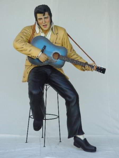 Elvis Presley sitting on stool playing guitar